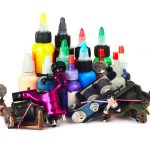 Tattoo machine with many color ink bottles isolated white background